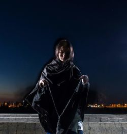 Midsection of woman standing against illuminated lights at night