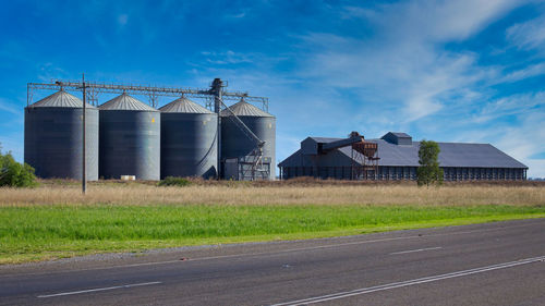 Built structure on field by road against sky