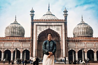 Full length of temple standing outside building against sky in city