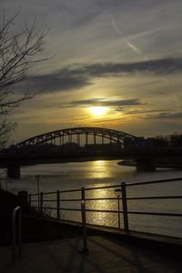 Bridge over river against sky at sunset