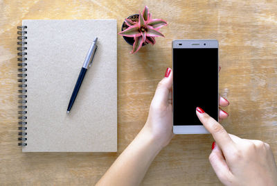 Cropped hands of woman using mobile phone over table