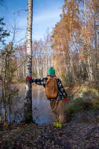 Rear view of man standing on tree trunk