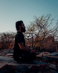 Side view of man sitting on rock