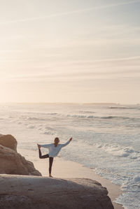 Man standing on rocks at beach against sky