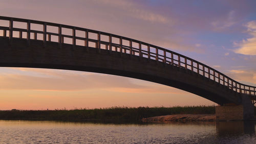 Bridge over river against sky during sunset