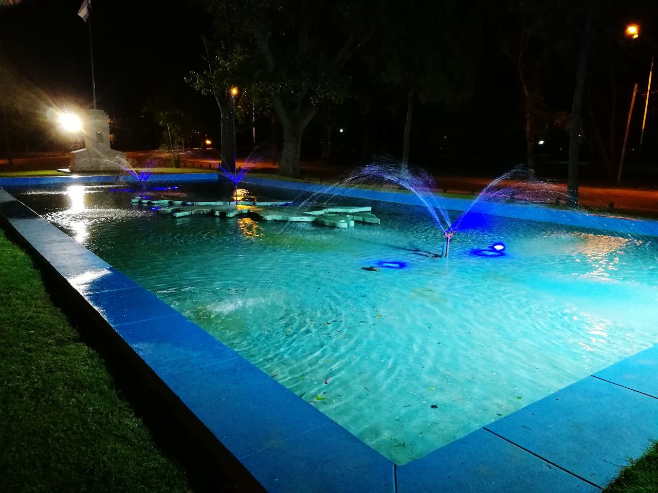 water, swimming pool, night, illuminated, motion, outdoors, no people, blue, spraying, tree, nature