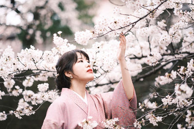 Portrait of young woman with pink cherry blossoms in spring