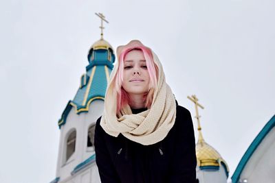 Portrait of young woman standing against church