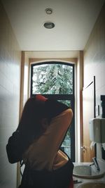 Rear view of woman standing at home