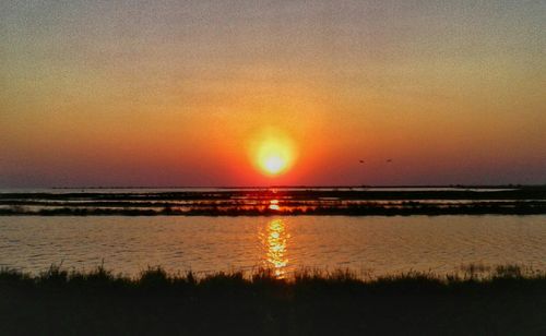 Scenic view of sea against dramatic sky during sunset