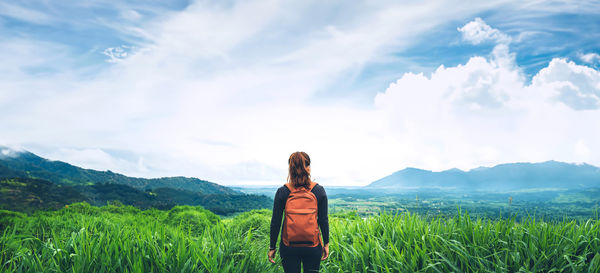 Rear view of woman standing on field against sky