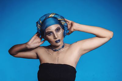 Portrait of young woman wearing headdress against blue background