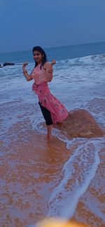 Woman with umbrella on beach against sky