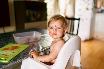 Portrait of baby girl sitting by table at home