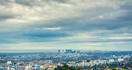High angle view of city buildings against cloudy sky