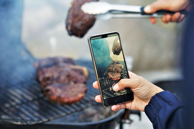 Midsection of person photographing with mobile phone