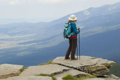 Rear view of man standing on rock by lake