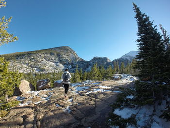 Rear view of man walking on mountain against clear blue sky