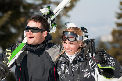 Happy mid adult couple with snowboards looking away