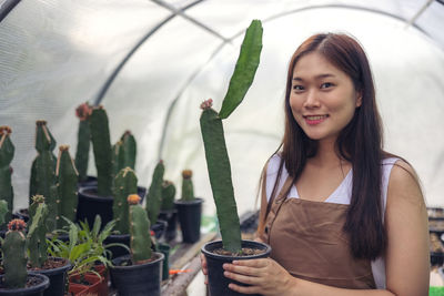 Portrait of smiling young woman holding potted plant
