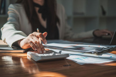 Midsection of businesswoman working on table