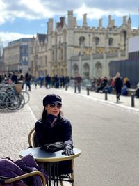 Rear view of woman sitting on street in city