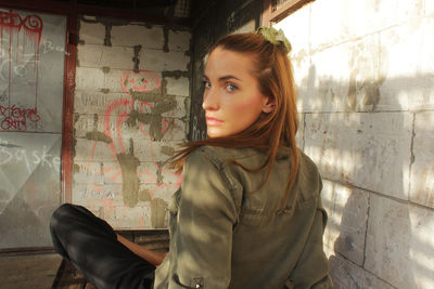 Portrait of young woman standing against wall