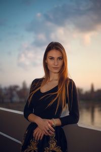 Portrait of beautiful young woman standing against sky