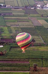 Multi colored hot air balloon flying over field