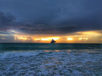 Scenic view of sea against dramatic sky during sunset