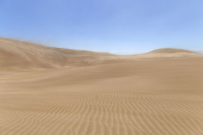 Scenic view of desert against clear blue sky