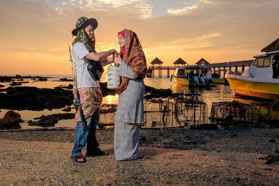 Full length of couple standing by seashore