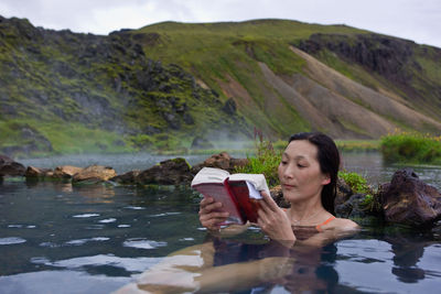 Woman reading book in thermal pool at landmannalaugar