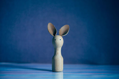 Close-up of animal representation on table against blue background