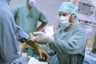 Assistant helping surgeon putting on glove before an operation