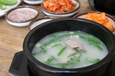 Korean pork rice soup or dwaeji-gukbap in a steaming stone bowl with the side dishes, busan