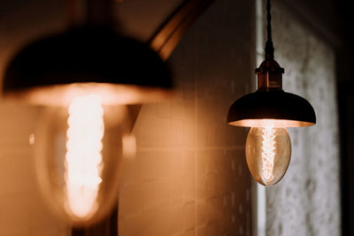 Low angle view of illuminated light bulb hanging on ceiling