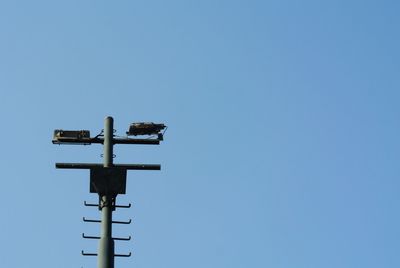Low angle view of weather vane against clear blue sky