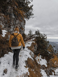 Rear view of young woman hiking on snowy path in mountains