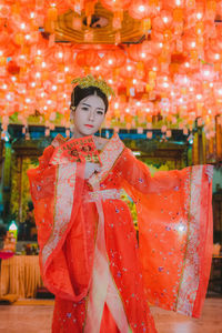 Portrait of young woman in traditional clothing standing at shrine