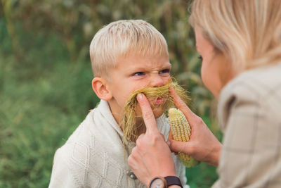 Happy preschooler boy playing with mom outdoors, having fun in corn field