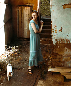 Portrait of a young woman standing against wall