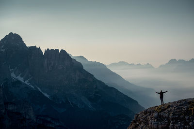 Rear view of man standing on mountains against sky