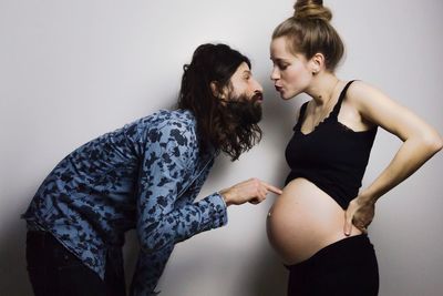 Man with pregnant woman standing against gray background