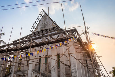 Low angle view of cranes on building against sky