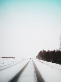 Road amidst snow covered trees against sky