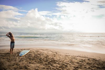 Full length of man standing on shore at beach against sky