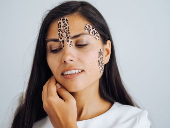 Young beautiful brunette woman with long hair with leopard tapes on her face