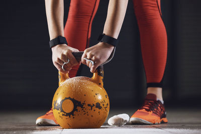 Low section of woman holding kettlebell on floor