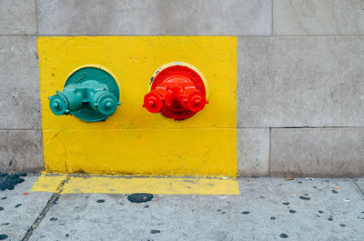 Fire hydrants on wall by sidewalk